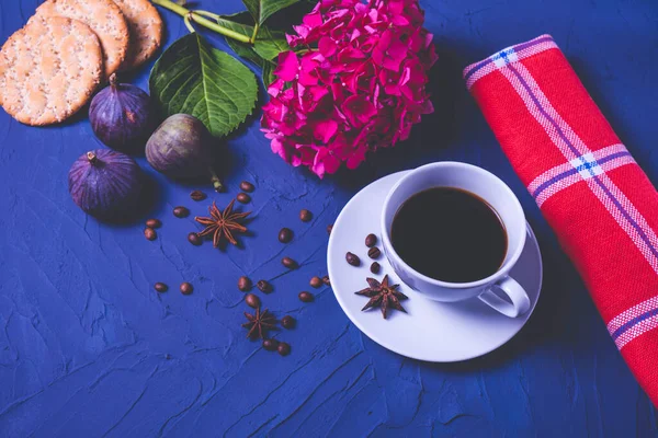 Sıcak kahve, kraker, olgun üç incir, aromatik kahve taneleri, anason ve mavi desenli arka planda kırmızı peçete standı