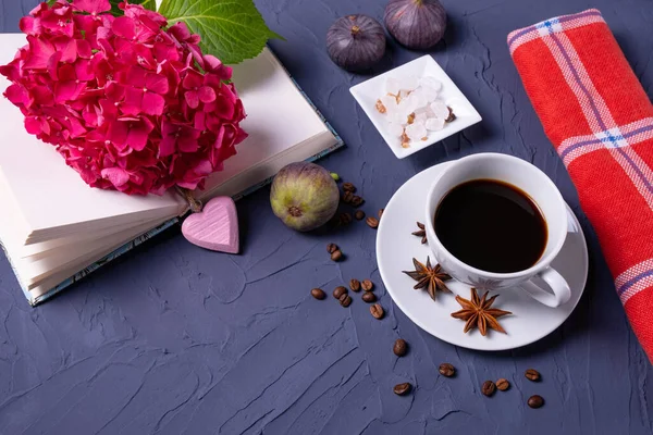 aromatik kahve, kahve çekirdekleri ve şeker küpleri, açık kitap ve mavi doku arka planında ortanca dalı