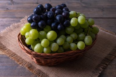 Tahta bir masadaki sepetin içinde toplanmış olgun sulu üzümler.