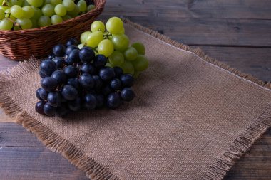 Hasat edilmiş, üzüm demetleri, köydeki kaba keten bir masa örtüsü ve ahşap bir masa üzerinde yatıyor.