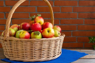 Bahçeden toplanmış olgun elma sepeti ahşap bir masada duruyor.