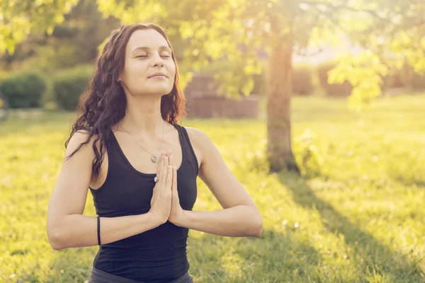 Junge kaukasische Frau beim Yoga im Park. sitzt im Lotus p Stockbild