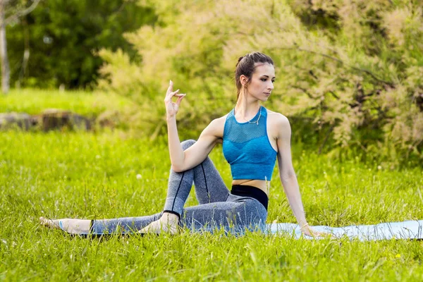 Junge kaukasische Frau macht Yoga im Park. — Stockfoto