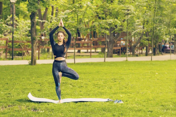 Junge kaukasische Frau macht Yoga im Park. — Stockfoto