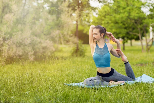 Junge kaukasische Frau macht Yoga im Park. — Stockfoto