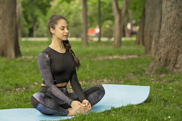 Junge kaukasische Frau macht Yoga im Park. — Stockfoto