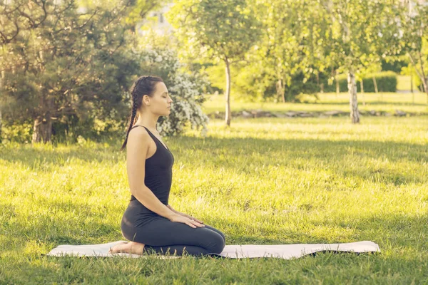Junge kaukasische Frau beim Yoga im Park. Meditierendes Sitzen — Stockfoto