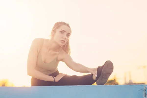 Een jonge vrouw maakt benen strekken in het park. — Stockfoto