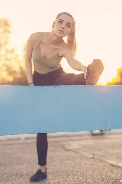 Genç bir kadın parkta bacak esnetiyor.. — Stok fotoğraf