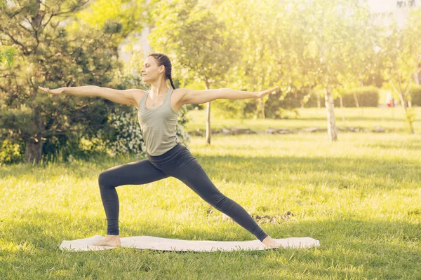 Junge kaukasische Frau beim Yoga im Park. er breitet seine Hand aus — Stockfoto