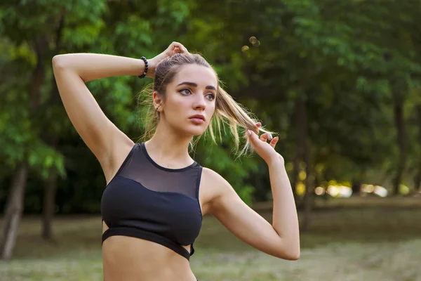 Eine junge Frau mit schönen Titten treibt im Park Sport Stockfoto