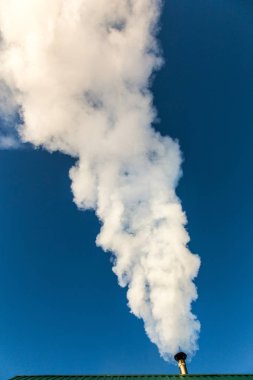 Mavi gökyüzüne karşı evin baca duman gelir. Boru çatıda. Baca. Kır evi.