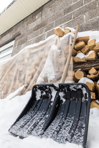 Eine Schaufel Zum Reinigen Von Schnee Der Nähe Eines Brennholzstapels — Stockfoto