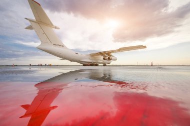 Bir büyük Rus kargo uçağı hava ve su arka planı onun yansıması bir bulutlu gökyüzü ve gün batımı