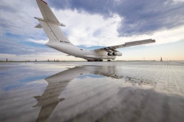 Bir büyük Rus kargo uçağı hava ve su arka planı onun yansıması bir bulutlu gökyüzü ve gün batımı