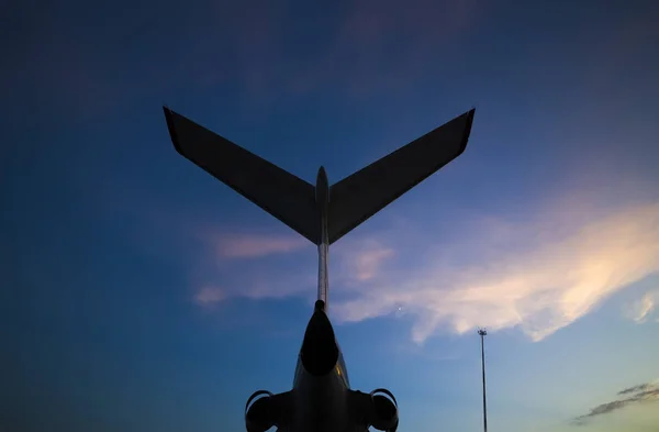 雲と夕日と空に対して空港でエンジンを搭載した航空機の尾のシルエット — ストック写真