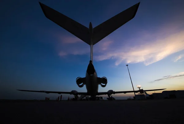 雲と夕日と空に対して空港でエンジンを搭載した航空機の尾のシルエット — ストック写真