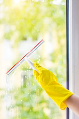 el ile deterjan ve kauçuk Alüminyum cam pencere bölmesini Temizleme silecek. Bir erkek parlak sarı eldiven yıkar pencereler eller.