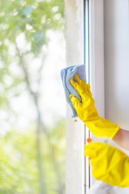 Parlak sarı lastik eldiven kadın elinde yıkar. yumuşak bir bez ile pencere temizleme. Güzel görünüm penceresinde