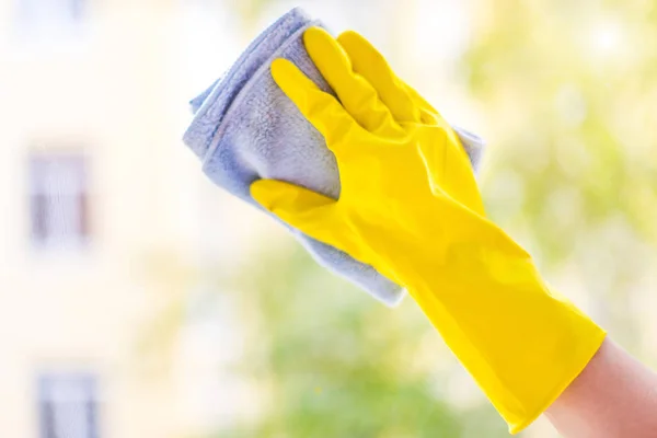 明るい黄色のゴム手袋で女性の手を洗います 柔らかい布でウィンドウをクリーニングします 窓からの眺め — ストック写真