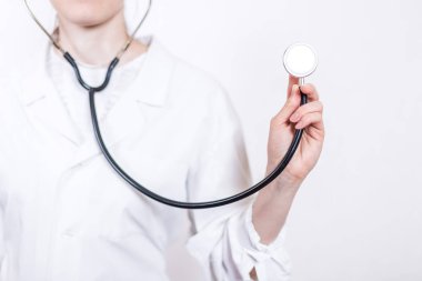 Stetoskop yakın çekim beyaz bir arka plan üzerinde çalışan genç gülümseyen kadın esmer doktor gözlük ve tıbbi beyaz önlük,