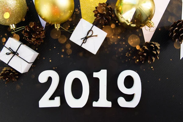 Happy New Years layout. numbers 2019 notepad and free space for text. Christmas decorations, Christmas toys, gold stars, gifts. Goals for the new year. mock up on black backround