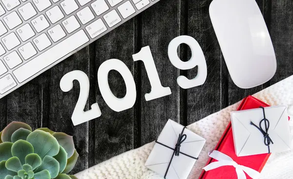 Una vista superior del espacio de trabajo con un ratón y un teclado sobre el fondo de madera oscura. frases en pegatinas. Plan 2018 — Foto de Stock