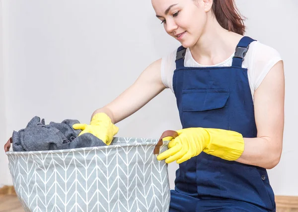 Cleaning service with equipment during work. women in uniform, overalls and rubber gloves woman puts dirty laundry in the basket, cleaning the apartment, washing machine. Isolated on white, free space