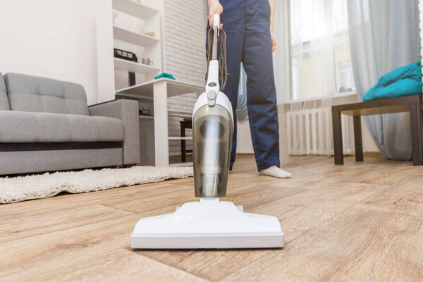 Уборка с профессиональным оборудованием во время работы. Химчистка ковров, химчистка дивана, мытье окон и полов. женщины в форме, комбинезоне и резиновых перчатках
