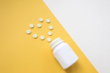 İlaç şişe ve beyaz hap üzerine sarı pastel renkli arka plan döktüm. İlaç ve reçeteli ilaç düz arka plan yattı. Opioid salgın