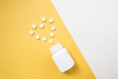 İlaç şişe ve beyaz hap üzerine sarı pastel renkli arka plan döktüm. İlaç ve reçeteli ilaç düz arka plan yattı. Opioid salgın.