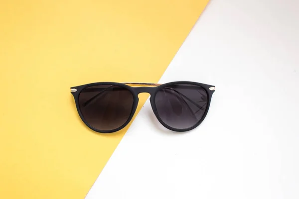 Μαύρα γυαλιά ηλίου σε λευκό και κίτρινο φόντο. μινιμαλισμός και καλοκαιρινή μόδα για την παραλία — Φωτογραφία Αρχείου