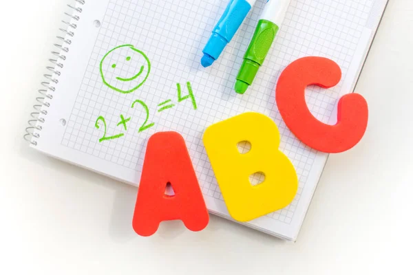 Educação na escola primária. um layout de letras ABC, um caderno e marcadores em um fundo branco. O início do ano letivo. Espaço livre para texto — Fotografia de Stock