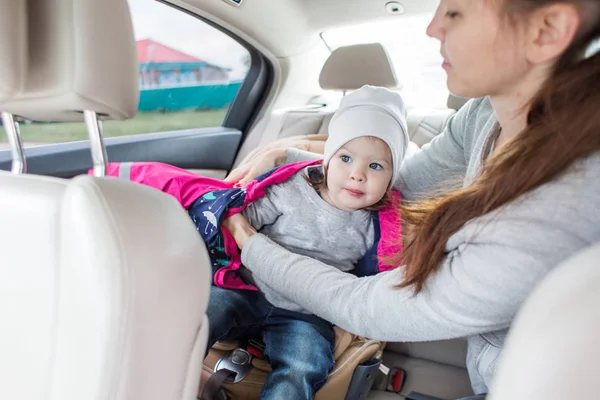 Baby in a child car seat. safe transportation of children. family travels. Mom quests his child in the car seat — Stock Photo, Image