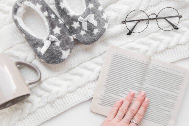 ev konfor ve kış akşam. yumuşak odak vintage gözlük, bir kitap kadın elini tutuyor. üstten görünüm ev terlik, bir kupa üzerinde bir örme halı flatlay. öğrenme, meslek Editör, redaktör, yazar