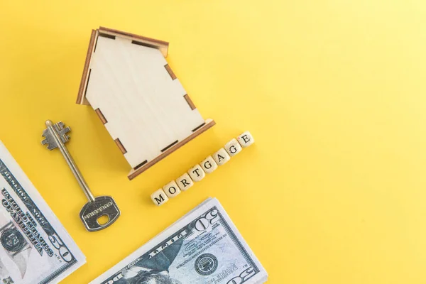 Mortgage, lån och köp. Modell av hus, dollarsedlar, nyckel på vita och gula isolerade bakgrund. Ledigt utrymme för text, flatlay — Stockfoto