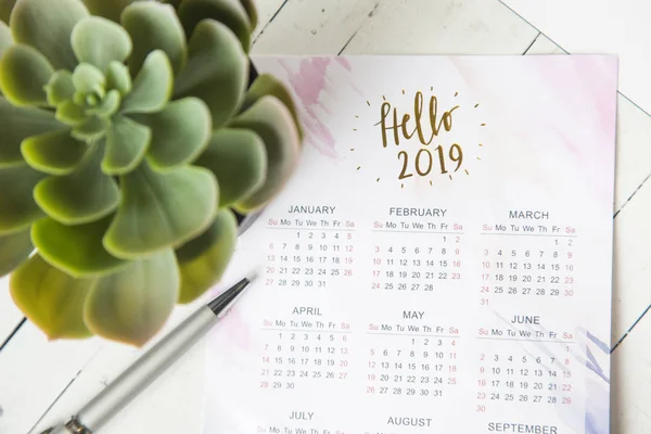 Calendario para 2019 en el escritorio de la oficina en un cuaderno. Planes y metas para el nuevo año. Diseño de vista superior sobre fondo blanco —  Fotos de Stock