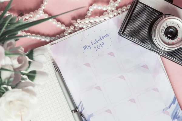 Calendário para 2019 na mesa de escritório em um caderno. Planos e metas para o novo ano. Layout de vista superior no fundo rosa, xmas flatlay — Fotografia de Stock