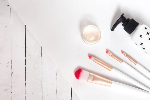 Beauty flat lay with cosmetic bottles, makeup brushes, jar of cream, succulent leaves and saw cut wood. Top view, minimalism, flatlay