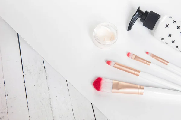 Beauty flat lay with cosmetic bottles, makeup brushes, jar of cream, succulent leaves and saw cut wood. Top view, minimalism, flatlay