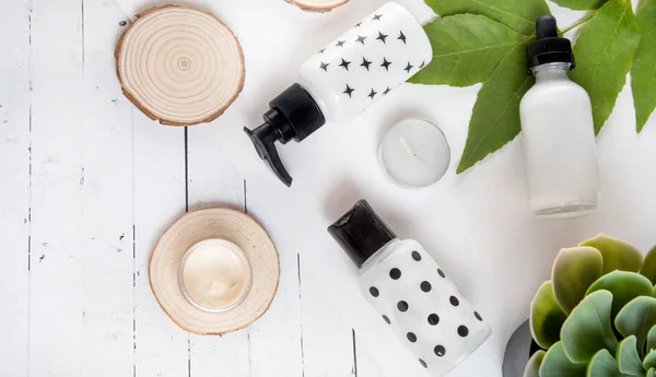 Beauty flat lay with spa cosmetic bottles, jar of face cream, succulent leaves and saw cut wood. Top view, minimalism, flatlay