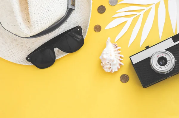 Flatlay cestovatel příslušenství na žlutém pozadí s Palmový list, mince, shell, Starý fotoaparát a sluneční brýle. Pohled shora cestování nebo koncept dovolenou a letní pozadí — Stock fotografie