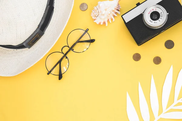 Accesorios de viaje Flatlay sobre fondo amarillo con hoja de palma, moneda, concha, cámara vieja y gafas de sol. Top view concepto de viajes o vacaciones y fondo de verano — Foto de Stock