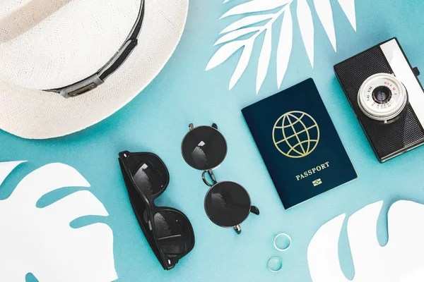 Flatlay akcesoria podróżnika na niebieskim tle z liść palmowy, aparat fotograficzny, paszport i okulary przeciwsłoneczne. Widok z góry podróży lub wakacje koncepcja. Lato na tle. — Zdjęcie stockowe
