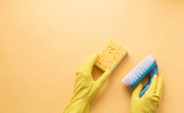 Låg lägenheten rengöringsmedel och rengöring av tillbehör och kvinnors händer i gummihandskar i gul färg. Rengöring servicekoncept. Flatlay, ovanifrån. — Stockfoto