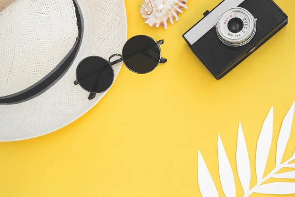 Accessori per viaggiatori Flatlay su sfondo giallo con foglia di palma, moneta, guscio, vecchia macchina fotografica e occhiali da sole. Vista dall'alto concetto di viaggio o vacanza e sfondo estivo — Foto Stock