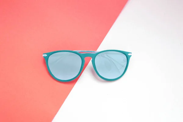 blue sunglasses on pink and white background. minimalism and summer fashion for the beach. Color of the year 2019 Living coral