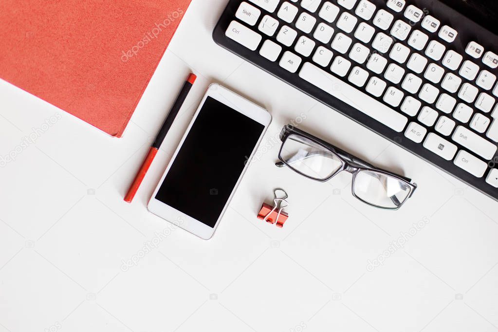 phone, glasses, pen, notebook keyboardpaper clips on office desk. color of the year 2019 Living coral
