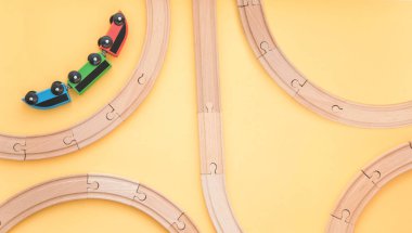 Çocuk oyuncakları sarı arka planda, oyuncak ahşap demiryolu ve tren. Üst Manzara. Flatlay. Metin için alanı kopyala