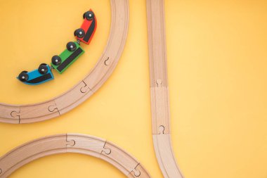 Çocuk oyuncakları sarı arka planda, oyuncak ahşap demiryolu ve tren. Üst Manzara. Flatlay. Metin için alanı kopyala